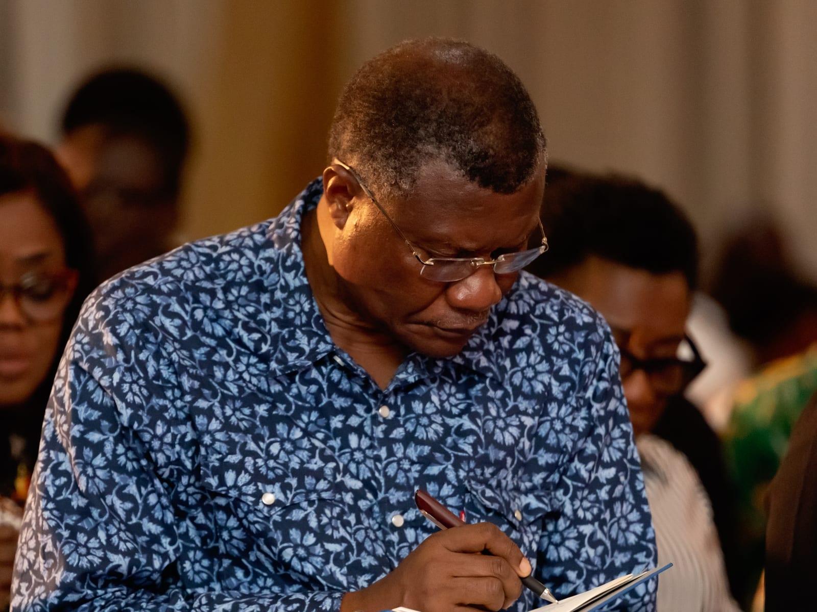 A man studying his Bible and writing notes during a service